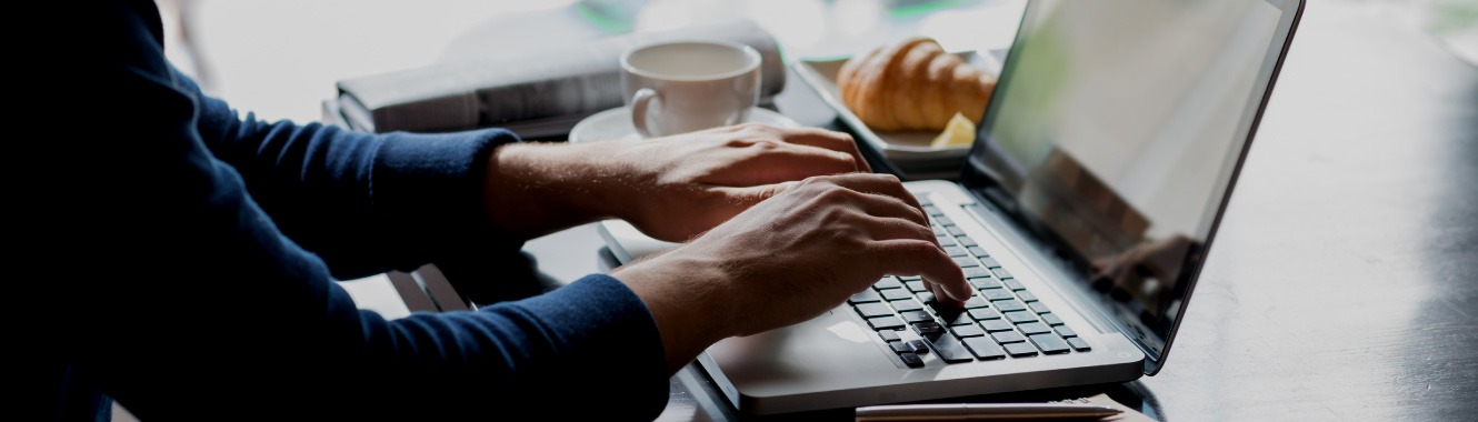 A person typing on computer at coffee shop